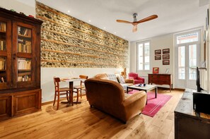 Una sala de estar con pared de piedra, muebles de madera, ventilador de techo y un comedor.