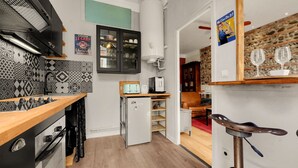 A compact kitchen with a modern stove, a small refrigerator, and a microwave. - L'Halo Gloire - Charmant T2 de caractère (Toulouse)