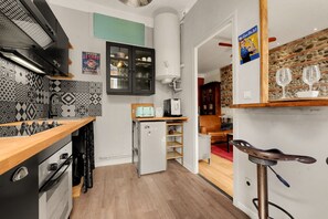 Una cocina compacta con estufa moderna, un refrigerador pequeño y un microondas.