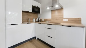 Una cucina moderna con mobili bianchi, un forno a microonde, una macchina da caffè e un piano di lavoro in legno.