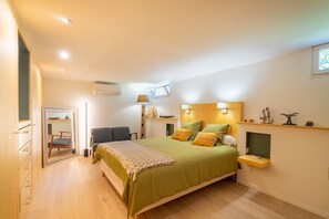Ein Schlafzimmer mit Bett, Nachttisch, Lampe und einem kleinen Regal mit Dekoration.