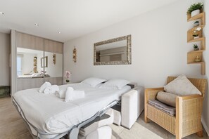 Ein modernes Schlafzimmer mit Bett, Stuhl, Spiegel und einem Regal mit Pflanzen.