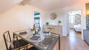 Un comedor con una mesa de vidrio, sillas y una cocina al fondo.