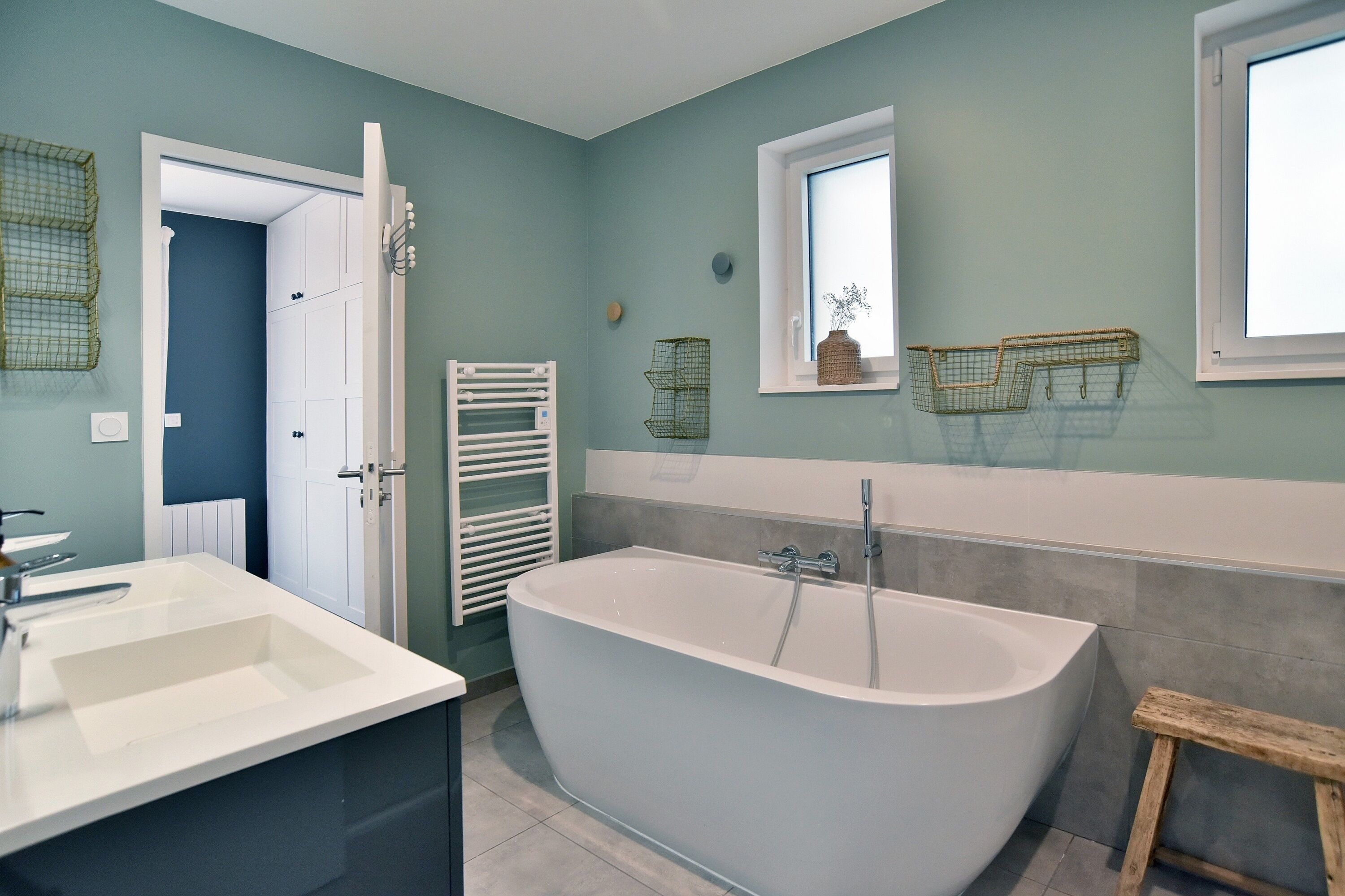 Un baño moderno con una bañera independiente, un tocador blanco y un ventanal con vistas.