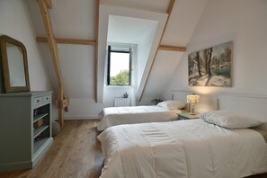 Ein Schlafzimmer mit zwei Betten, einem Fenster, einem Bild und einem Nachttisch mit Lampe.