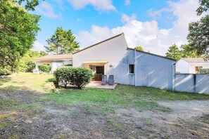 Einbungalow mit Satteldach, einer kleinen Veranda und einem gepflasterten Einfahrt.