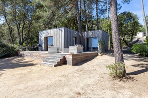 Eine moderne Holzjagdhaushälfte mit einer Terrasse, umgeben von Bäumen.