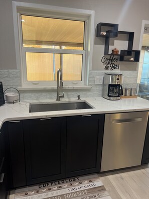 A kitchen with a sink, a coffee maker, and a window with blinds. - The Cozy Coastal Retreat with screened patio and arcades (Sarasota)
