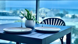 A dining table with two plates, a vase with white flowers, and two wine glasses. - Residence Surfers Ocean and Pool Views (Surfers Paradise)