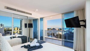 A modern hotel room with a large bed, a flat-screen TV, a balcony with a city view, and a sliding glass door. - Residence Surfers Ocean and Pool Views (Surfers Paradise)