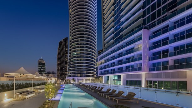 A modern hotel with a pool, multiple floors, and a curved facade. - Residence Surfers Ocean and Pool Views (Surfers Paradise)