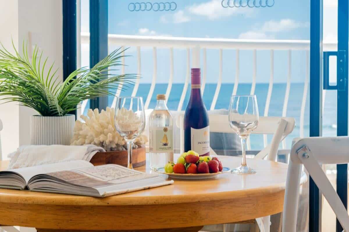 A table with a book, a bottle of wine, a glass, and a plate of fruit.
