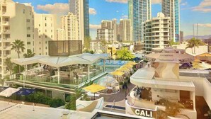 A modern hotel with a rooftop bar, glass-enclosed dining area, and a view of tall buildings. - Ocean View Studio 2 Beds Free WI-FI (Surfers Paradise)