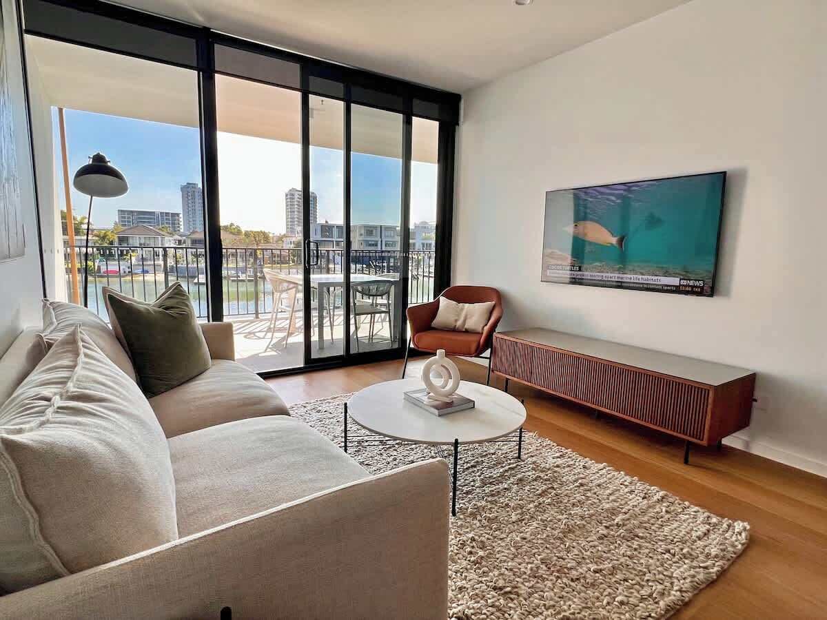 A modern living room with a sofa, coffee table, and a TV mounted on the wall.