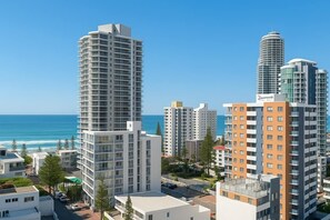 A high-rise hotel with a modern design, located near a beach with clear skies. - Ocean Getaway 1BR Heated Pool & Netflix (Surfers Paradise)