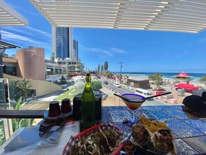 Ein Balkon mit Esstisch, der auf eine Stadtansicht und einen Strand blickt.