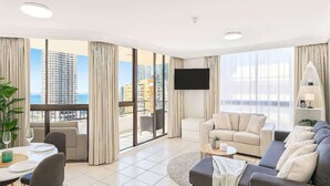 Un salon moderne avec balcon, un téléviseur à écran plat et un coin repas comprenant une table et des chaises.