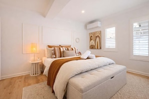 A bedroom with a bed, bedside table, lamp, and artwork on the walls.