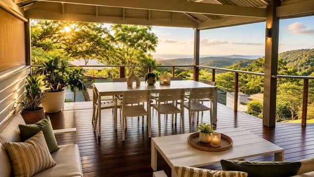 Un espace extérieur aménagé, abrité et doté de tables et de chaises, entouré de plantes en pot et offrant une vue sur un paysage montagneux.