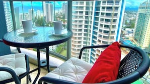 A balcony with a glass table, two chairs, and a red cushion. - L19 Ocean View Studio Near Beach Mantra Legends (Surfers Paradise)