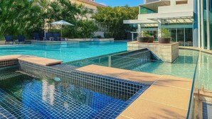 A swimming pool with clear blue water, surrounded by palm trees and modern buildings. - L19 Ocean View Studio Near Beach Mantra Legends (Surfers Paradise)