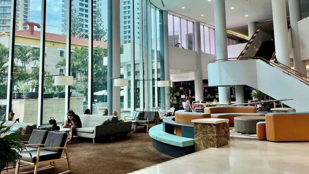 A spacious lobby with large windows, a curved staircase, and modern seating areas. - L19 Ocean View Studio Near Beach Mantra Legends (Surfers Paradise)
