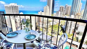 A balcony with a table and chairs, overlooking a cityscape and a pool. - L15 Ocean View Suite with 2 Beds (Surfers Paradise)