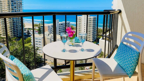 A balcony with a table, chairs, and a view of the ocean and buildings. - High Floor King Studio Surfers (Surfers Paradise)
