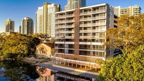A modern hotel with multiple floors, a central courtyard, and a reflection in the water. - Family apartment in Surfers Paradise (Surfers Paradise)
