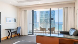 Ein Hotelzimmer mit Balkon, Schreibtisch, Stuhl, Sofa und Bett.