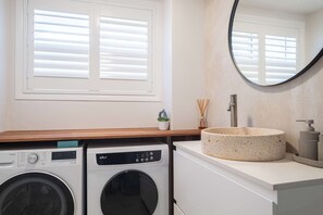A laundry area with a washing machine, dryer, and a sink with a round basin. - Charming Palm Beach Retreat with Pool & BBQ (Palm Beach)