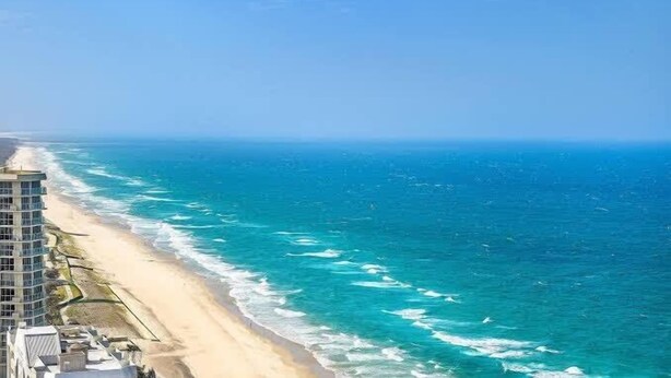 A coastal hotel with a beach view, a high-rise structure, and a clear sky. - Top level Ocean View Oasis: 3-Bed&Free Wi-Fi (Surfers Paradise)