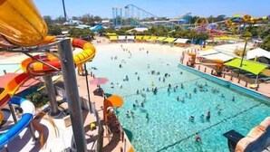 A water park with a large pool, slides, and a roller coaster in the background. - Top level Ocean View Oasis: 3-Bed&Free Wi-Fi (Surfers Paradise)