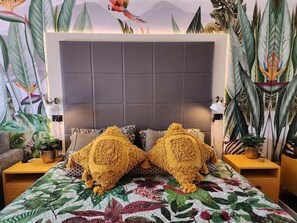A bed with a floral bedspread, two decorative pillows, a headboard, and a nightstand with a lamp. - Top Ocean View Artistic Apt (Surfers Paradise)