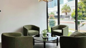 Una camera moderna con due poltrone verdi, un tavolino in vetro e un lampadario originale.