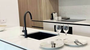 Una cucina moderna con un rubinetto nero, un'isola con piano in vetro e due bicchieri da vino.