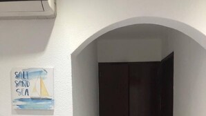 Un pasillo con una puerta oscura, un cartel con un velero y una unidad de aire acondicionado.