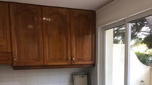 Una cocina con armarios de madera, una ventana, un lavamanos y una mesa de comedor.