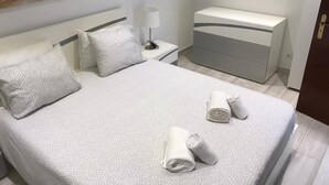 Una habitación de hotel con cama, mesita de noche, cómoda y un cuadro grande en la pared.