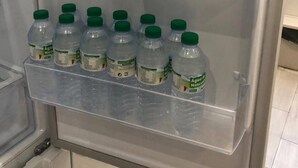 Un refrigerador con varios estantes, algunos conteniendo botellas de plástico transparente con tapas verdes.