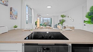 A modern kitchen with a built-in stove, a dishwasher, and a dining area with a view of the city.