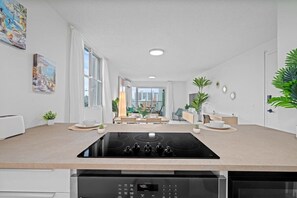 A modern kitchen with a built-in stove, a dishwasher, and a dining area with a view of the city. - High-Rise Condado Suite | Ocean Views & PR Skyline (San Juan)