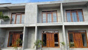 Un edificio de varios pisos con paredes exteriores de concreto, puertas de madera y balcones con barandillas.