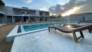 Un edificio moderno con piscina y sillones de descanso.