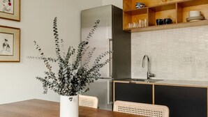 A modern kitchen with a wooden dining table, a potted plant, and a built-in oven.