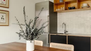 A modern kitchen with a wooden dining table, a potted plant, and a built-in oven.