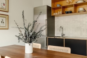 A modern kitchen with a wooden dining table, a potted plant, and a built-in oven. - Walker`s Paradise near Wash Park, Free Parking (Cincinnati)