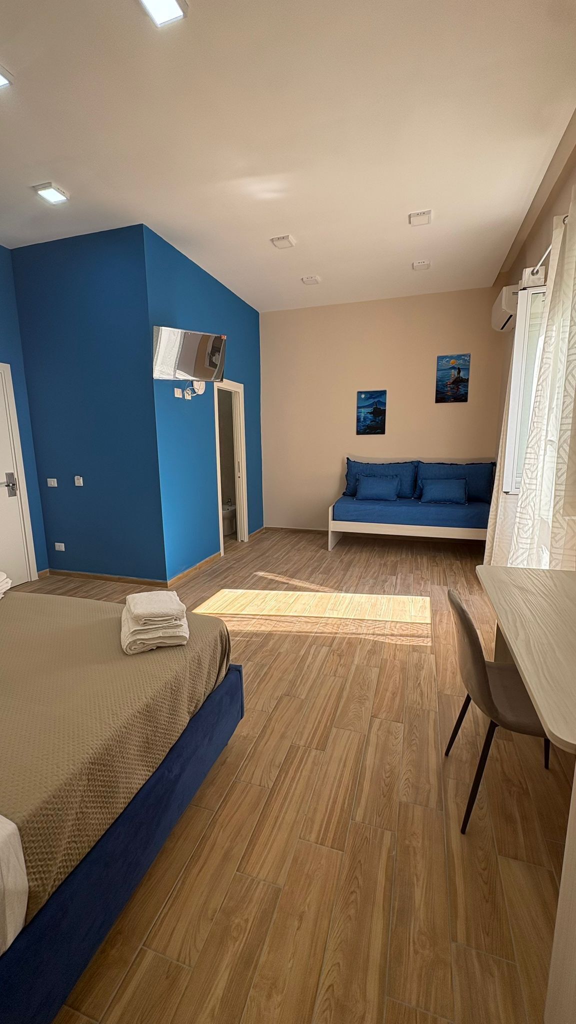 Una habitación con cama, escritorio, sofá y baño.