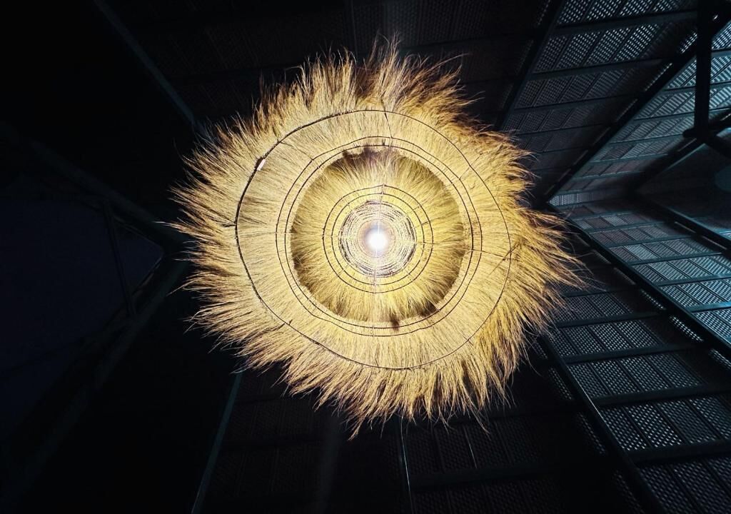 Una estructura circular iluminada con anillos concéntricos, sobre un fondo oscuro con un patrón similar a una cuadrícula.