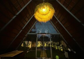 A room with a large glass window, a hanging light fixture, and a view of the outdoors.